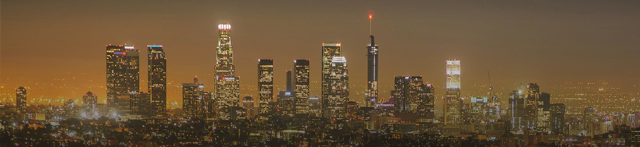 A nighttime cityscape featuring a skyline with illuminated skyscrapers and a glowing horizon.