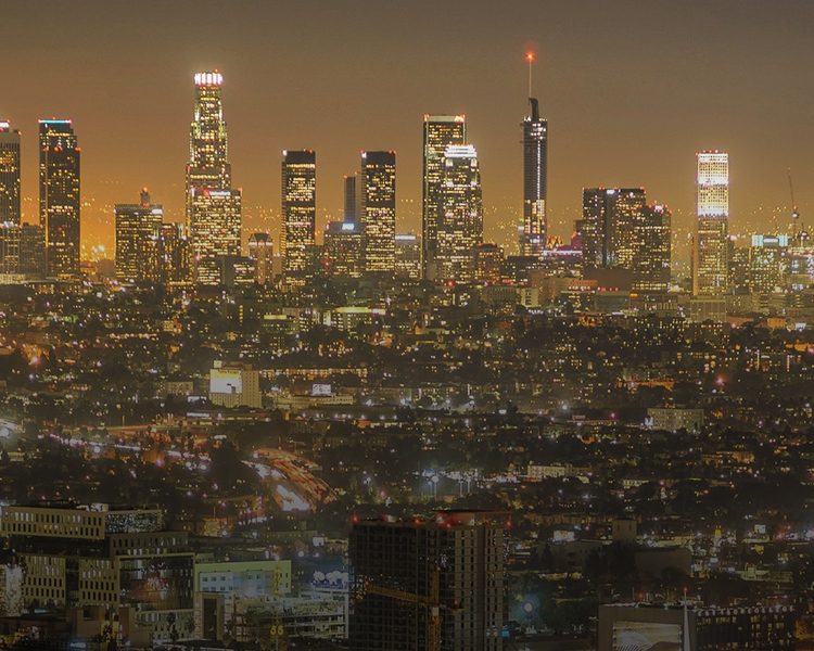 A nighttime cityscape featuring a skyline with illuminated skyscrapers and a glowing horizon.